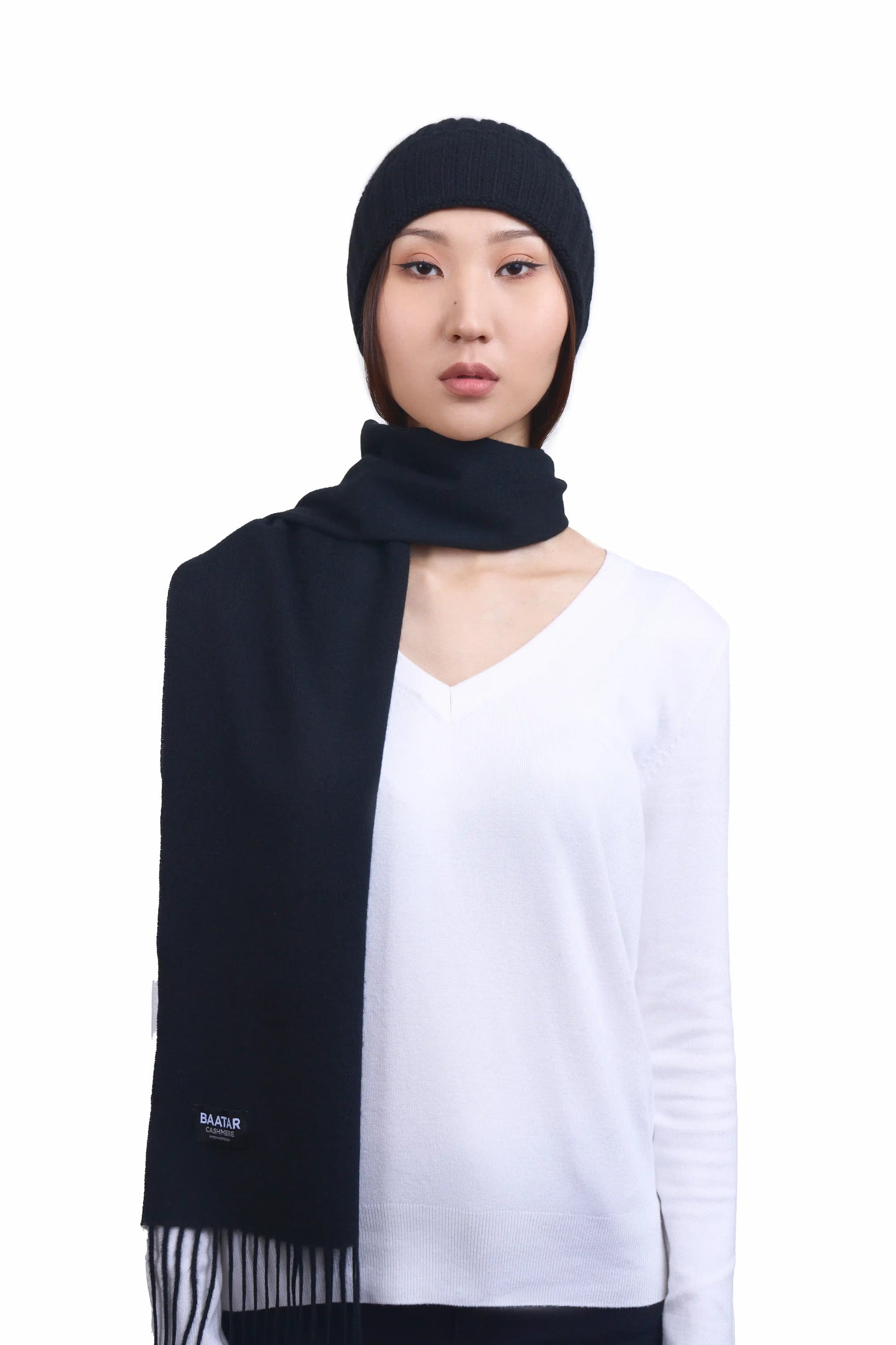 Mongolian female model wearing a soft black cashmere beanie and warm scarf, highlighting the luxurious texture and elegant design against a neutral background