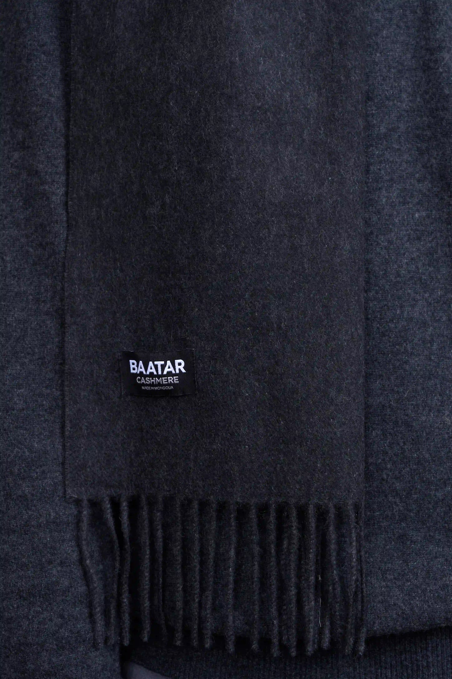 Warm charcoal gray Mongolian cashmere scarf draped elegantly on a gray sweater to highlight its softness and versatility.
