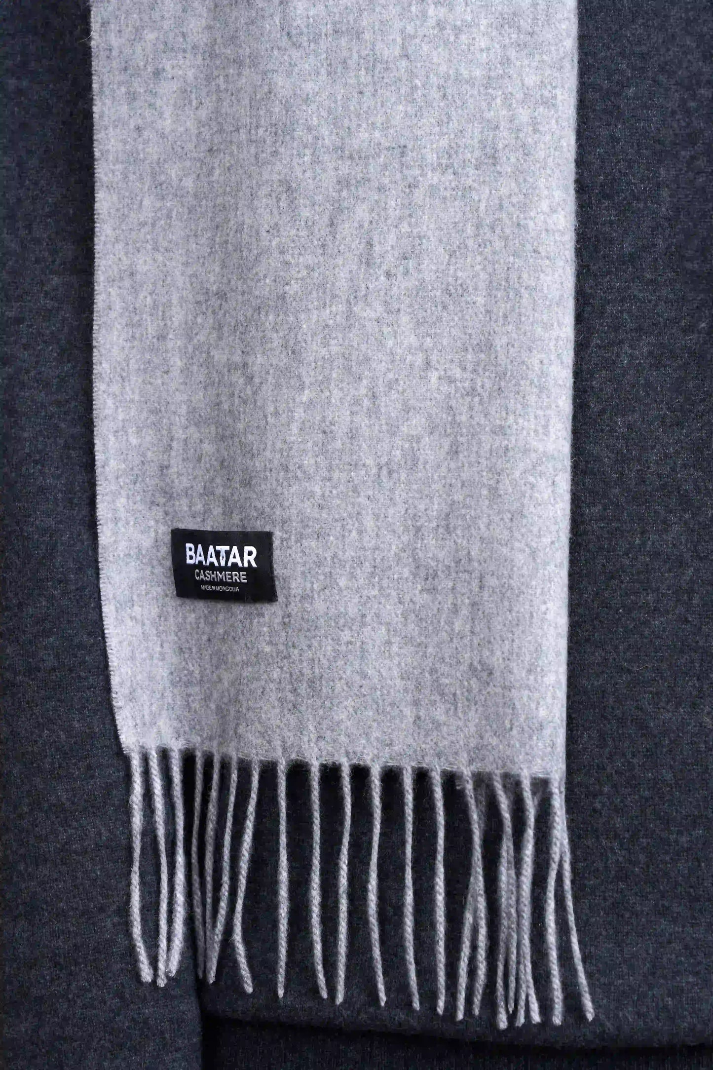 Warm light gray Mongolian cashmere scarf draped elegantly on a gray sweater to highlight its softness and versatility.