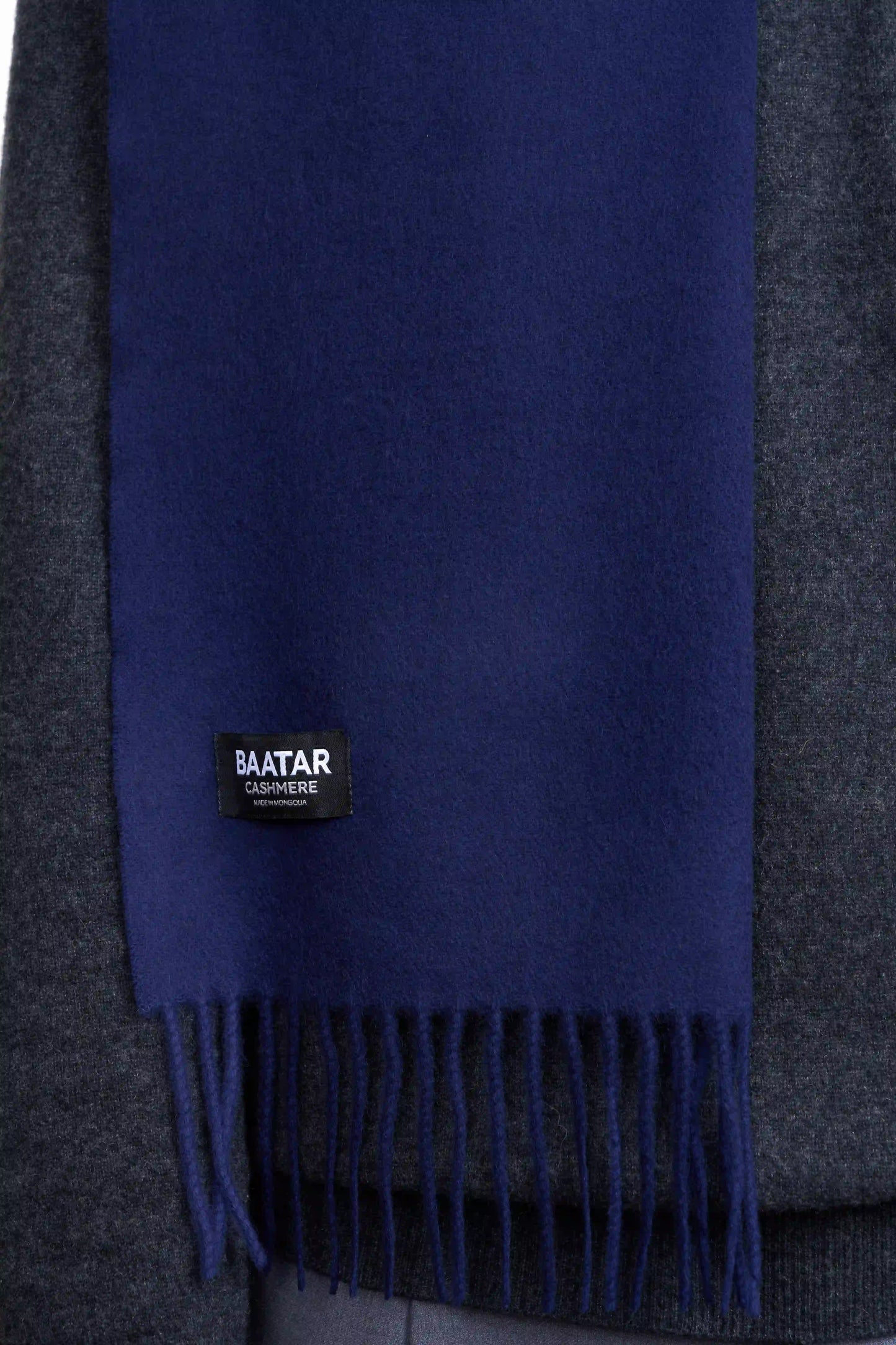 Warm navy blue Mongolian cashmere scarf draped elegantly on a gray sweater to highlight its softness and versatility.