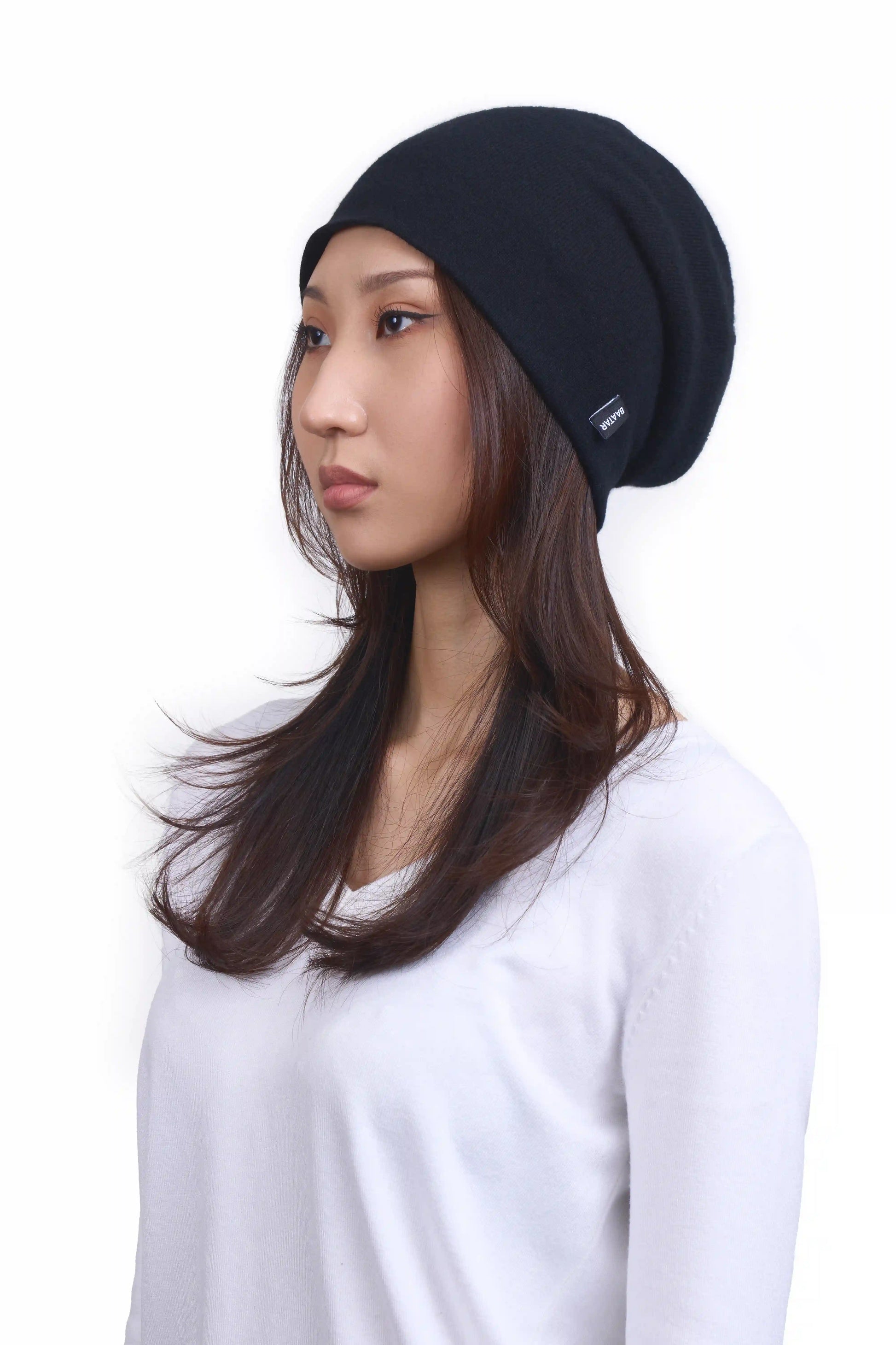 Mongolian female model in 3/4 view wearing a slouchy black cashmere beanie, highlighting the luxurious texture and elegant design against a neutral background