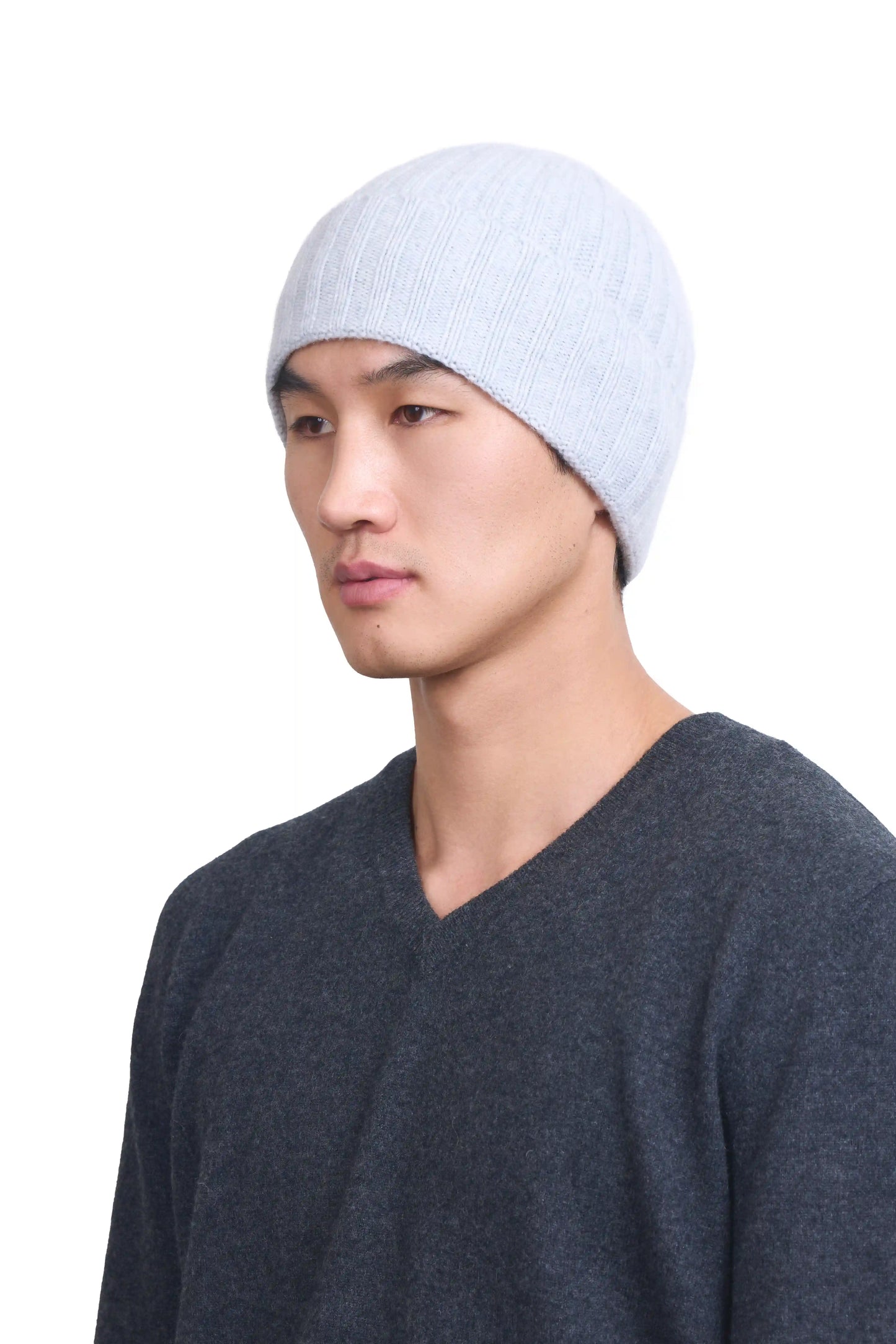 Mongolian male model in 3/4 view wearing a soft light gray cashmere beanie, highlighting the luxurious texture and elegant design against a neutral background