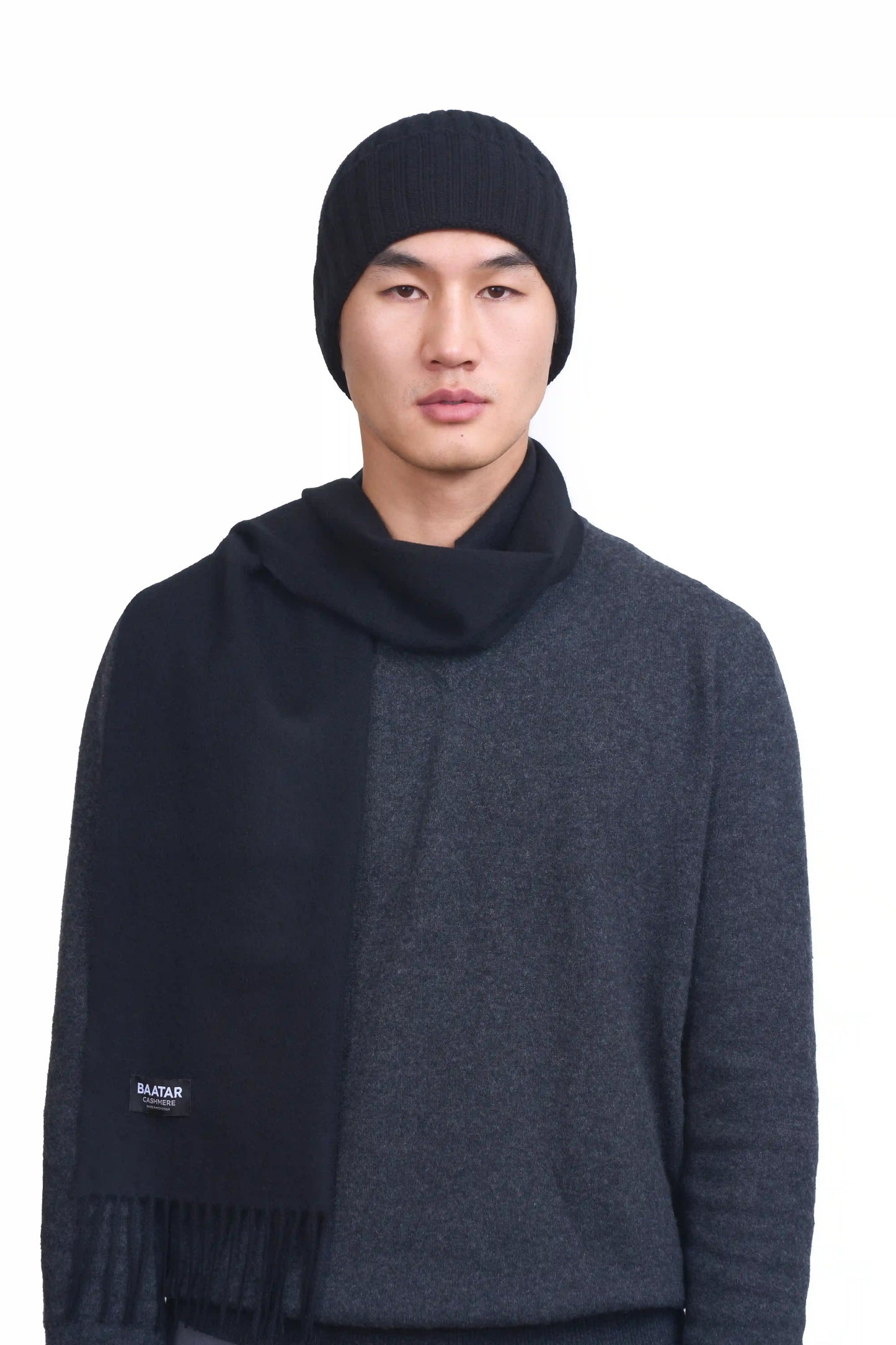 Mongolian male model wearing a soft black cashmere beanie and scarf, highlighting the luxurious texture and elegant design against a neutral background