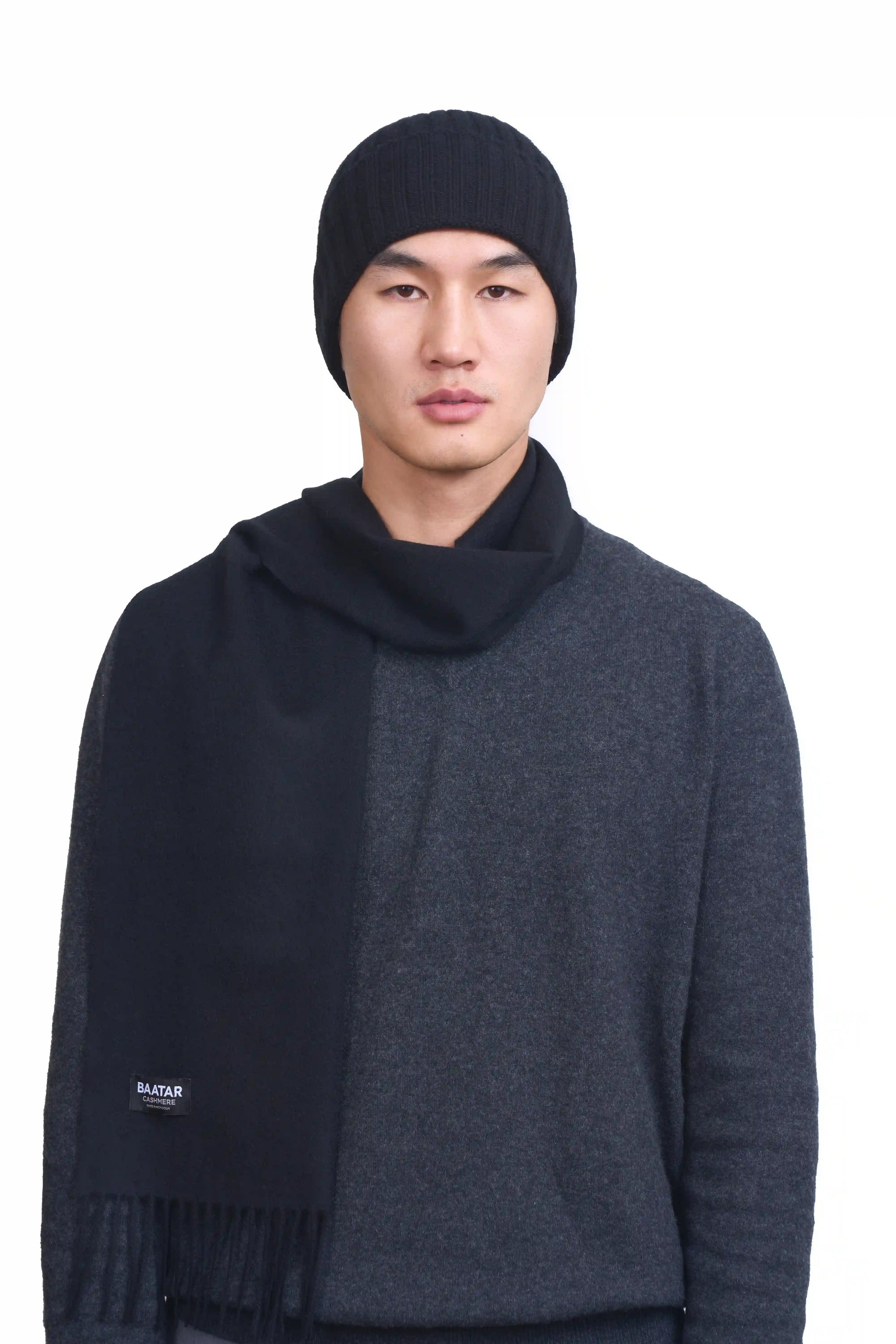 Mongolian male model wearing a soft black cashmere beanie and scarf, highlighting the luxurious texture and elegant design against a neutral background