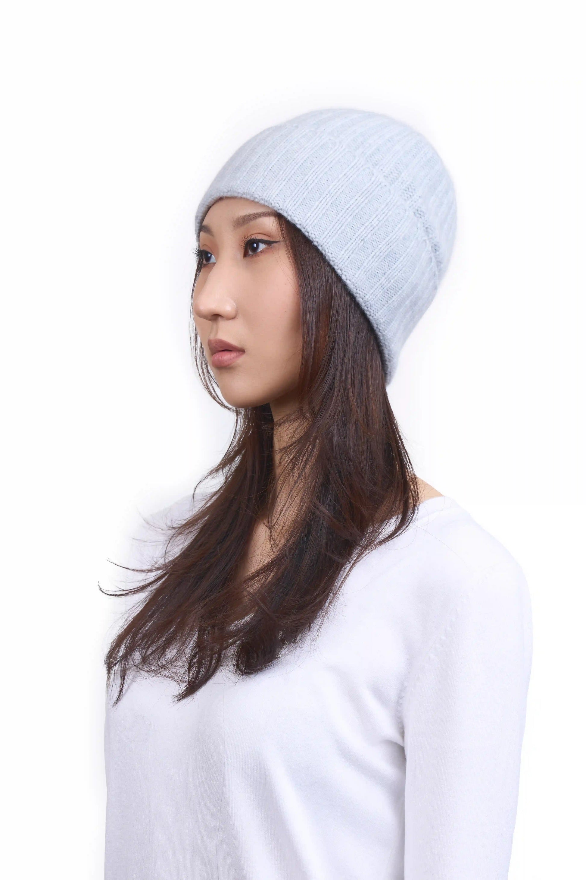 Mongolian female model in 3/4 view wearing a soft light gray cashmere beanie, highlighting the luxurious texture and elegant design against a neutral background