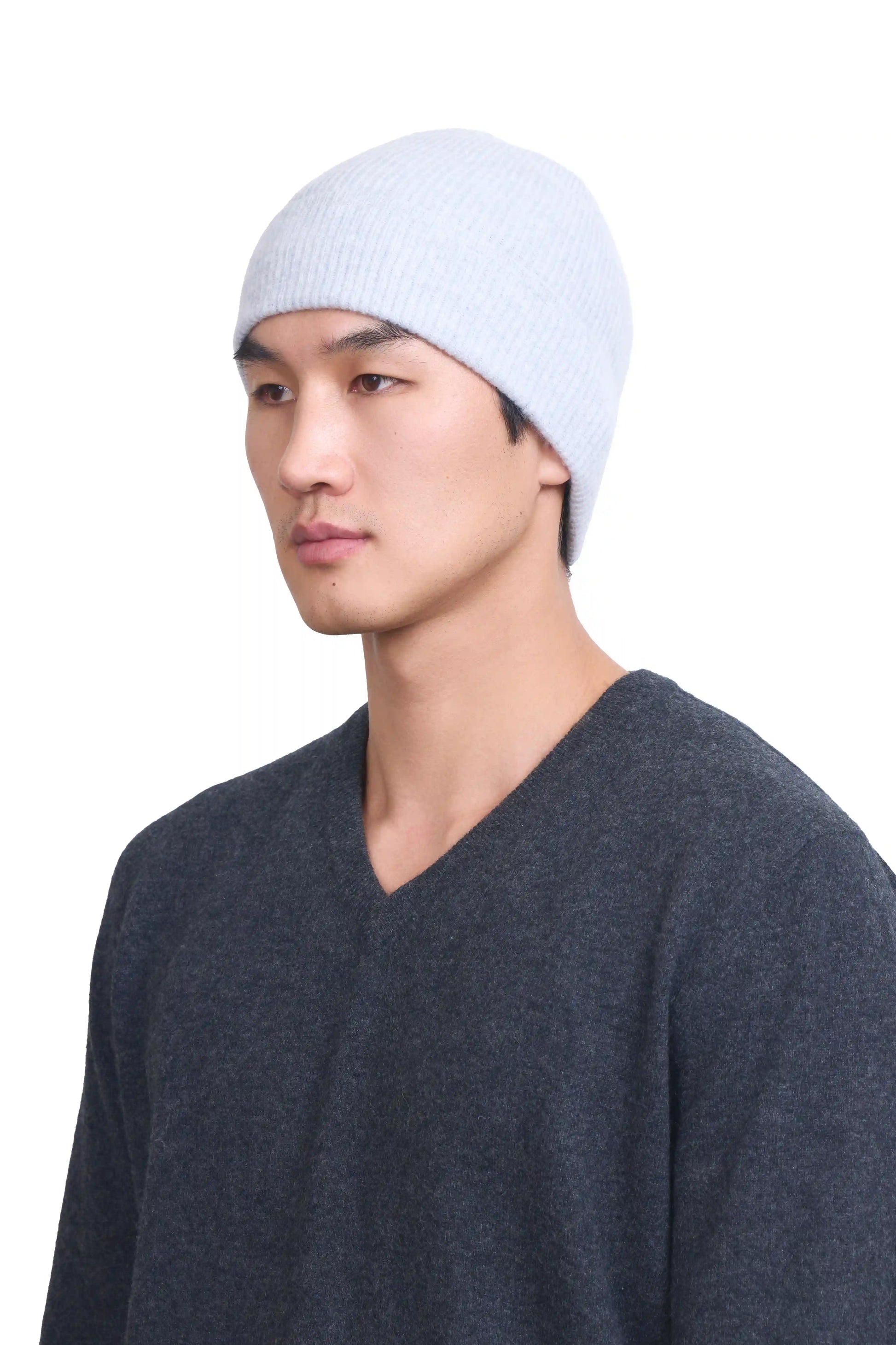 Mongolianmale model in 3/4 view wearing a soft light gray cashmere beanie, highlighting the luxurious texture and elegant design against a neutral background