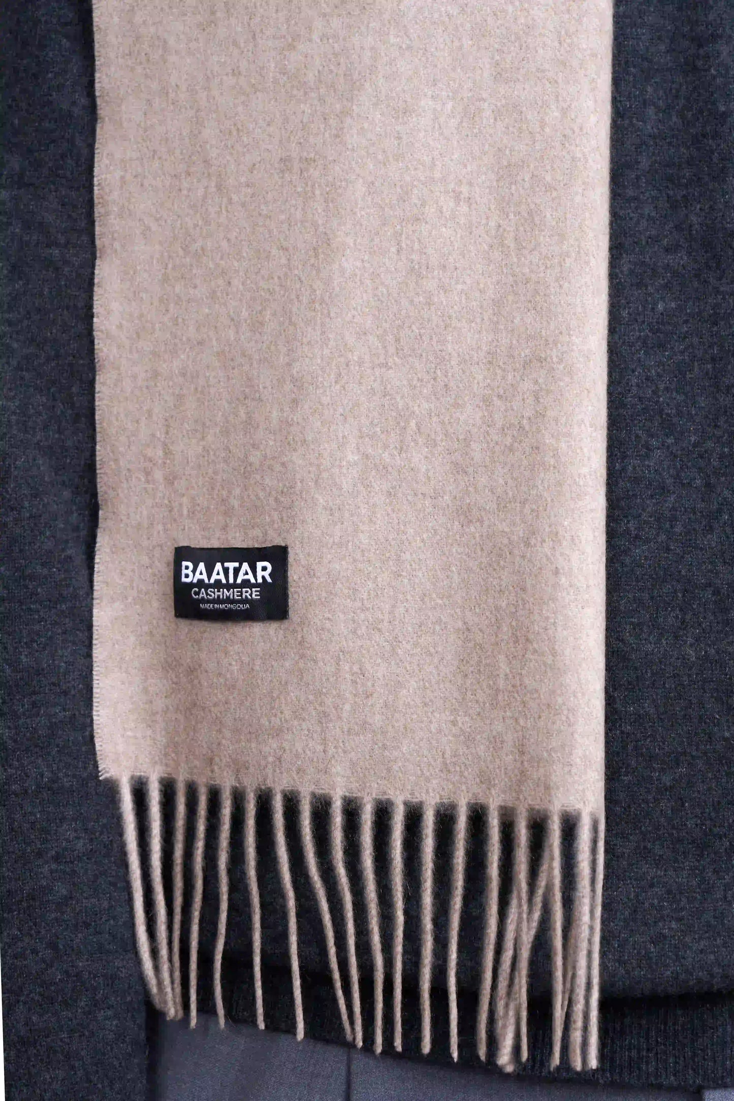 Warm natural beige Mongolian cashmere scarf draped elegantly on a gray sweater to highlight its softness and versatility.