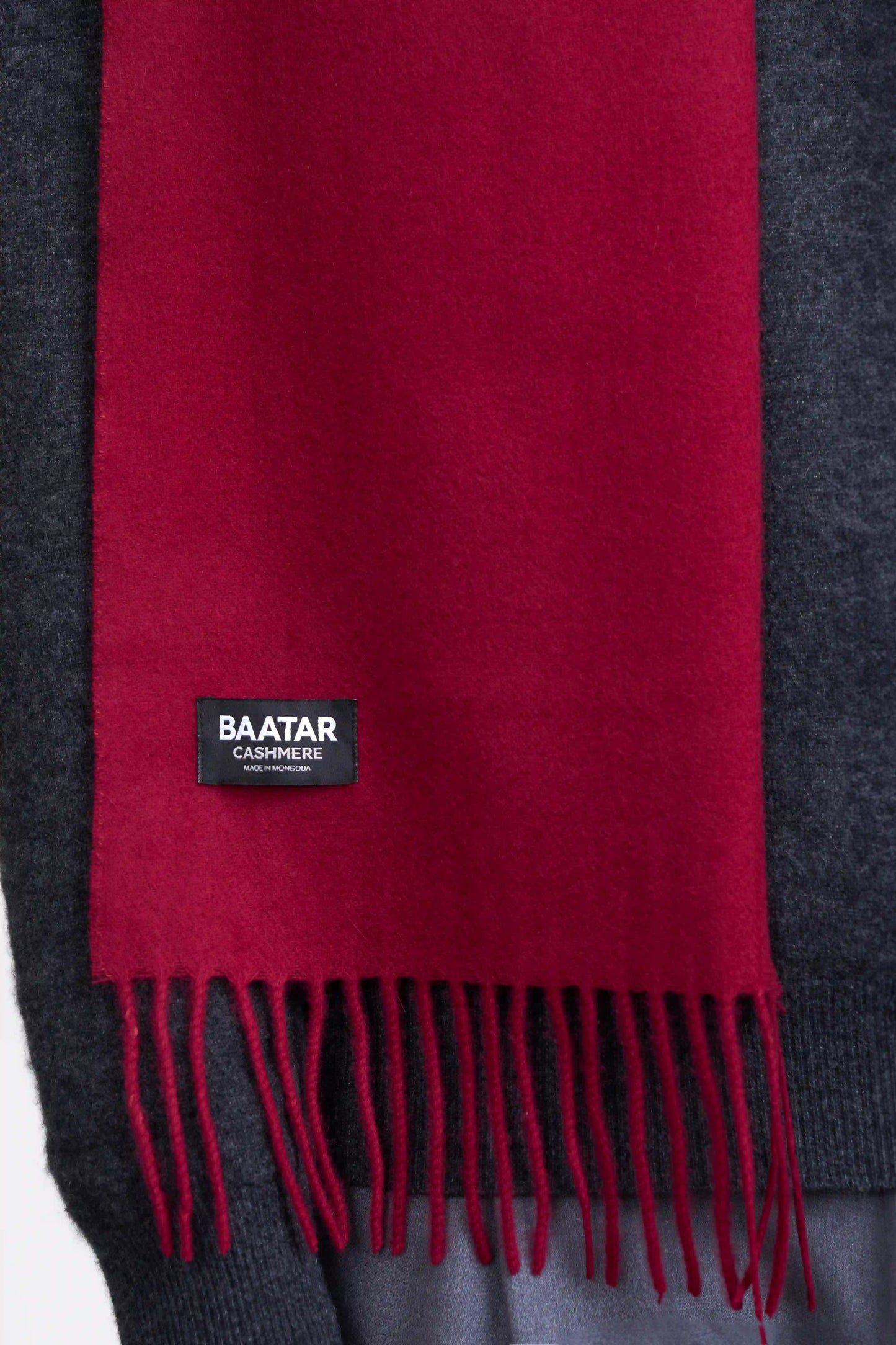 Warm burgundy red Mongolian cashmere scarf draped elegantly on a gray sweater to highlight its softness and versatility.