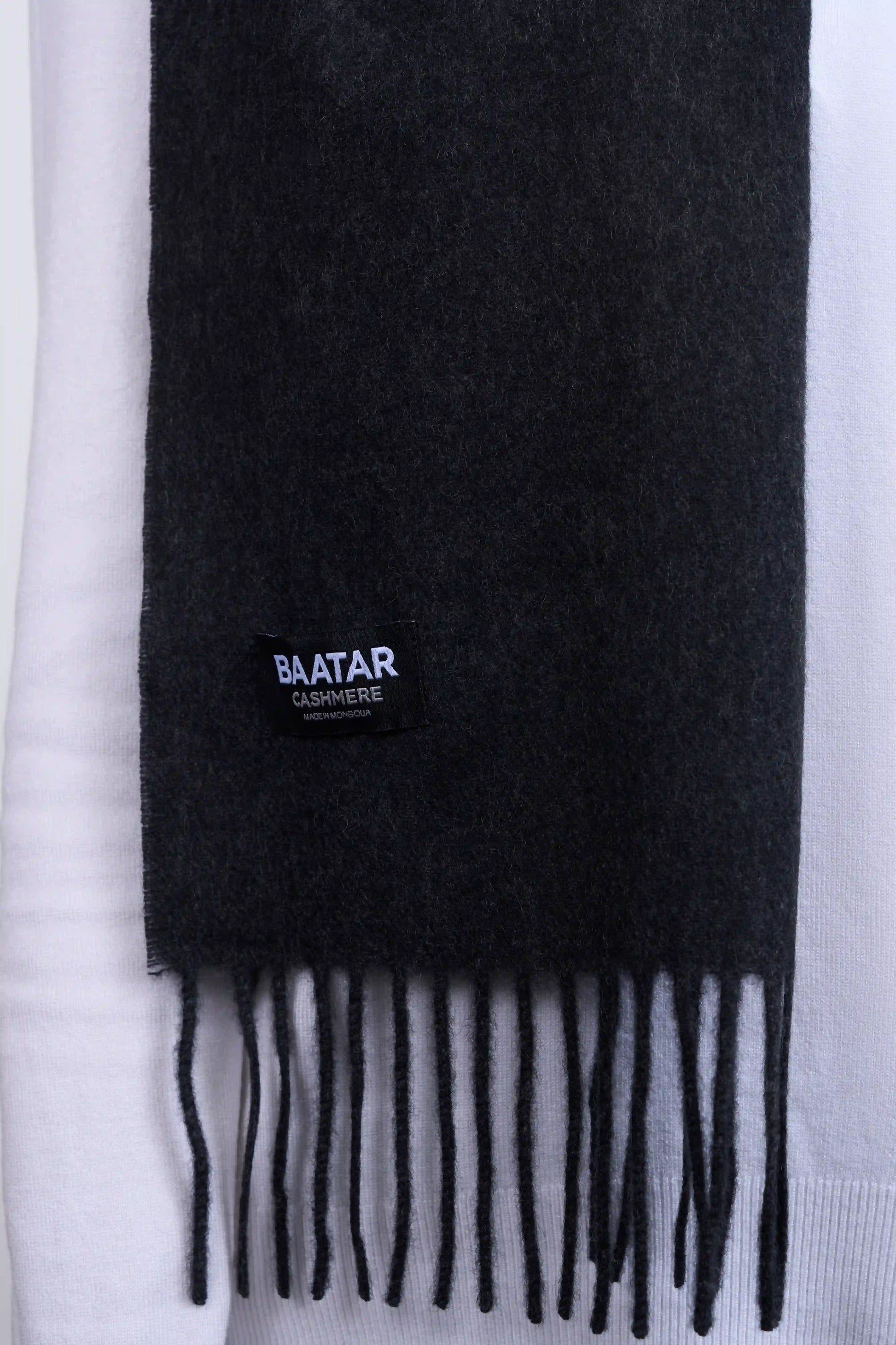 Warm charcoal gray Mongolian cashmere scarf draped elegantly on a white sweater to highlight its softness and versatility.