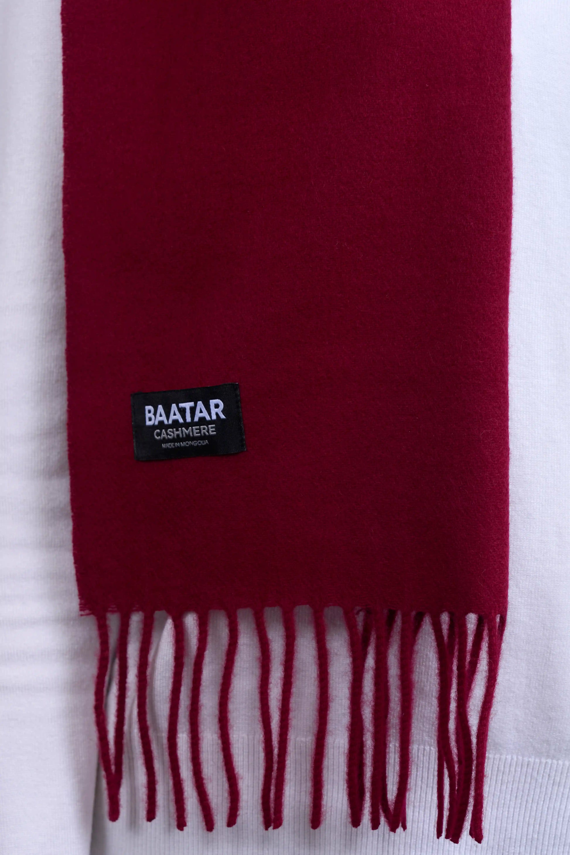 Warm burgundy red Mongolian cashmere scarf draped elegantly on a white sweater to highlight its softness and versatility.