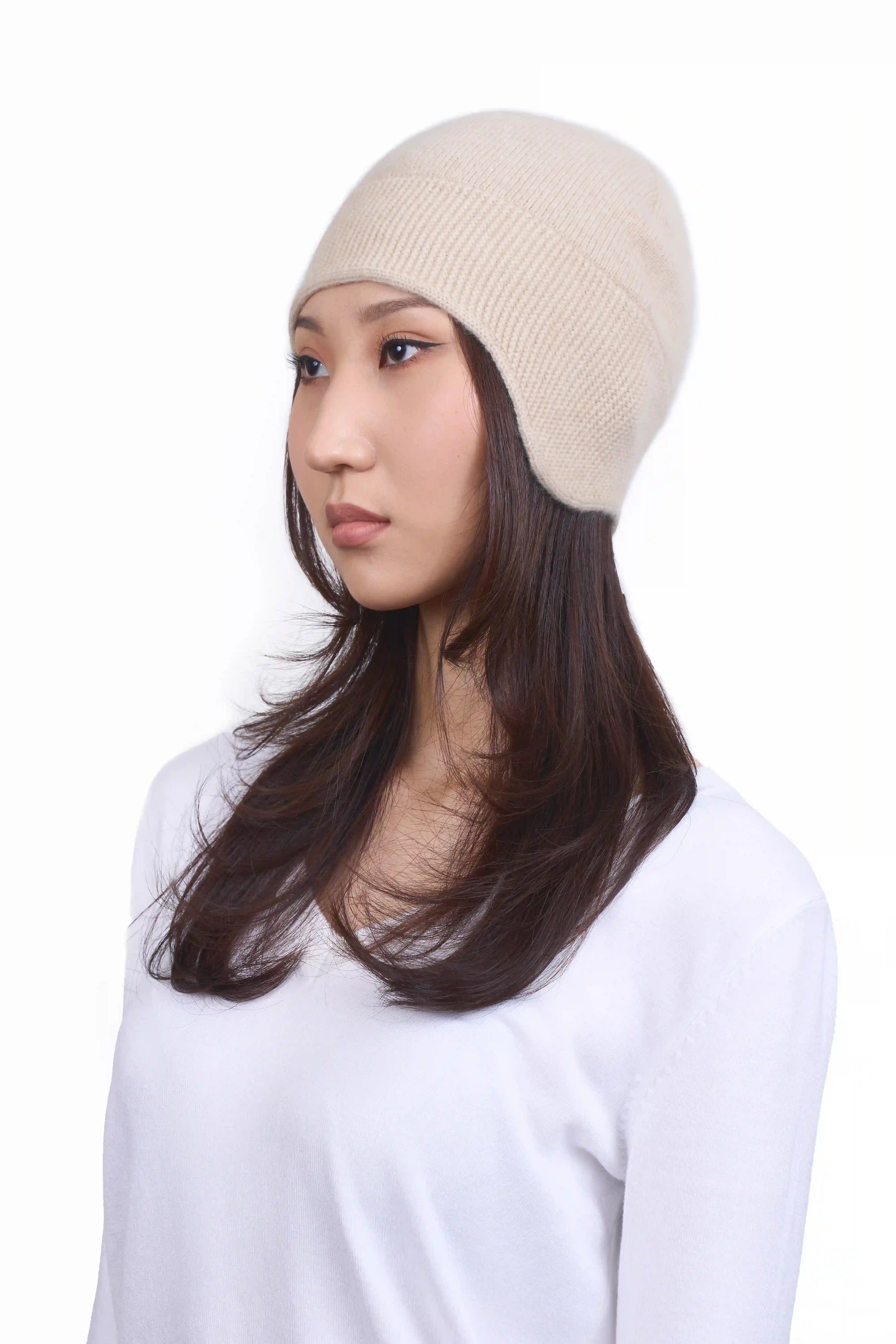Mongolian female model in 3/4 view wearing a soft natural beige cashmere beanie, highlighting the luxurious texture and elegant design against a neutral background